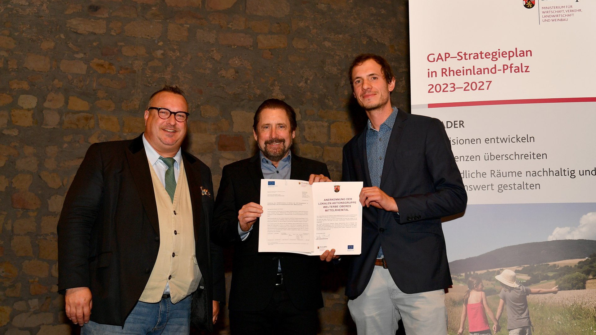 Staatssekret&auml;r Andy Becht (von links) &uuml;berreicht die Urkunde zur Anerkennung als LEADER-Region an Peter Unkel und Nico Melchior von der LAG Welterbe Oberes Mittelrheintal | &copy; Ministerium f&uuml;r Wirtschaft, Verkehr, Landwirtschaft und Weinbau