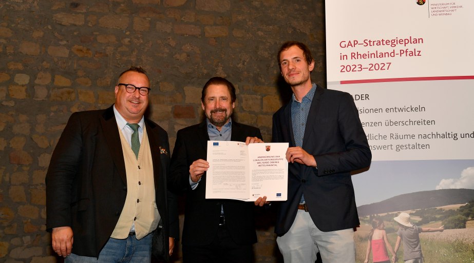 Staatssekret&auml;r Andy Becht (von links) &uuml;berreicht die Urkunde zur Anerkennung als LEADER-Region an Peter Unkel und Nico Melchior von der LAG Welterbe Oberes Mittelrheintal | &copy; Ministerium f&uuml;r Wirtschaft, Verkehr, Landwirtschaft und Weinbau